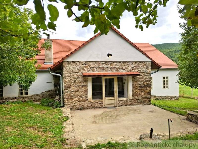 A family house in Dobroč with a stone facade, traditional roof, and a pleasant garden.