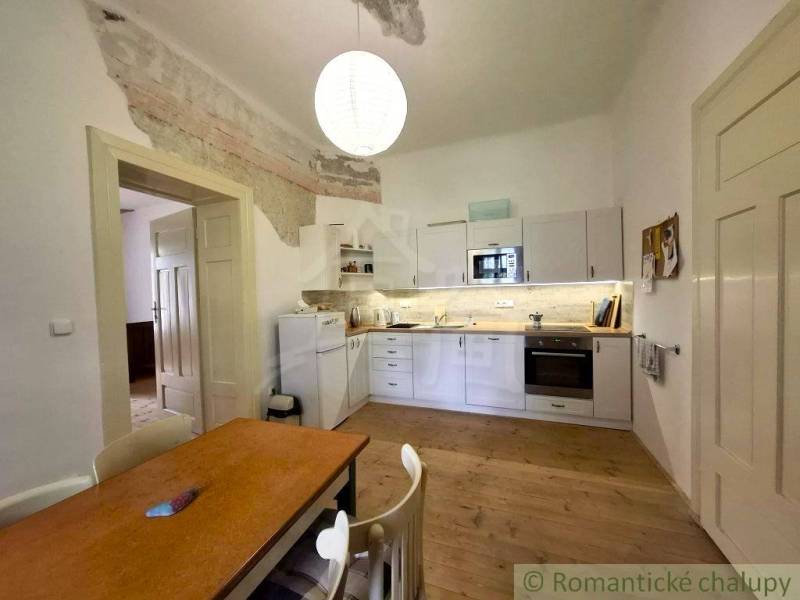 A kitchen with white furniture and a wooden decor floor in a family house.