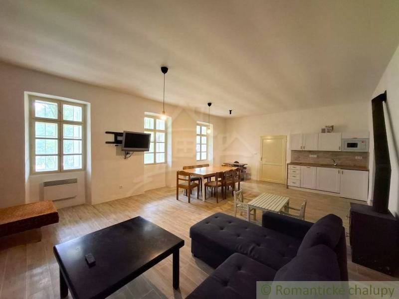Living room with kitchen in a family house, wooden decor flooring, dining table, sofa.