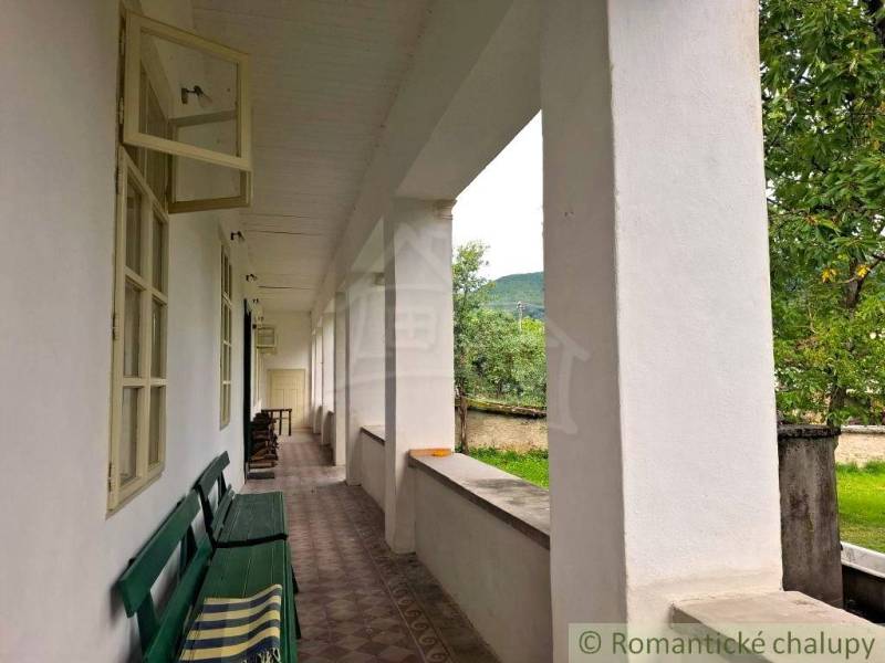 A veranda with a bench at a family house in Dobroč, overlooking the garden and trees.
