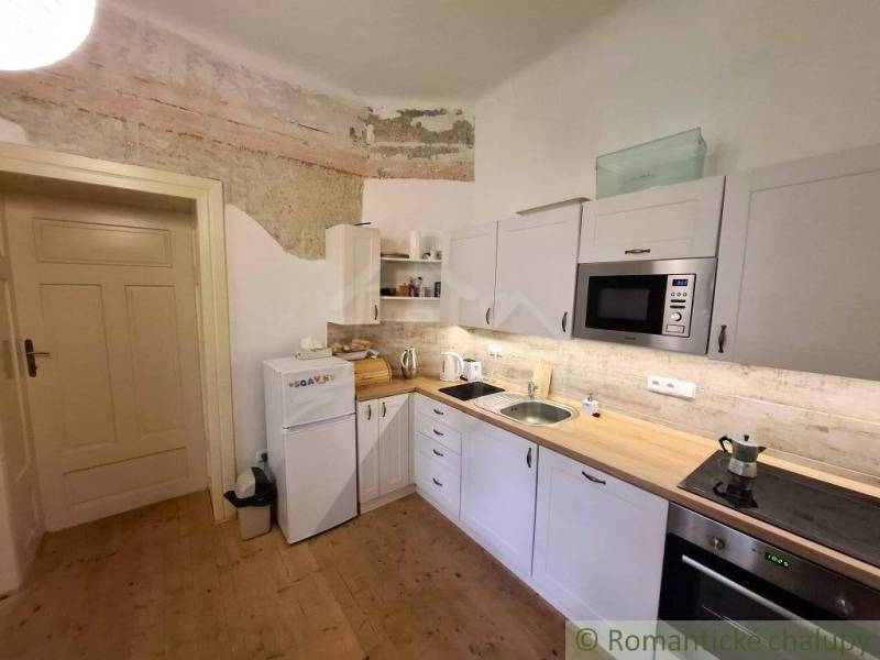 A kitchen in a family house with white cabinets and a wood-patterned floor.