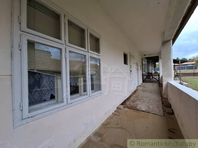 A veranda at a family house in Mužla with window blinds and a garden in the background.