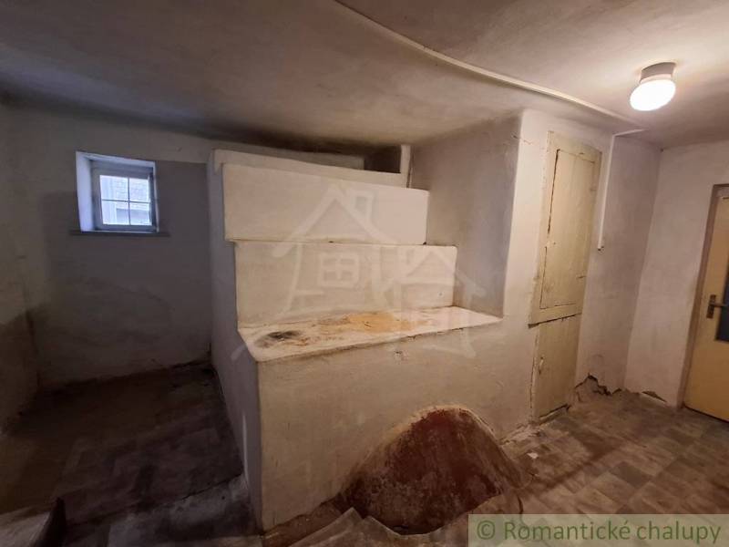 Interior of a family house with an old stove, a window, and a light on the ceiling.