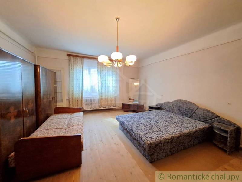 A bedroom in a family house with a double bed, a single bed, and a floor with a wooden decor.