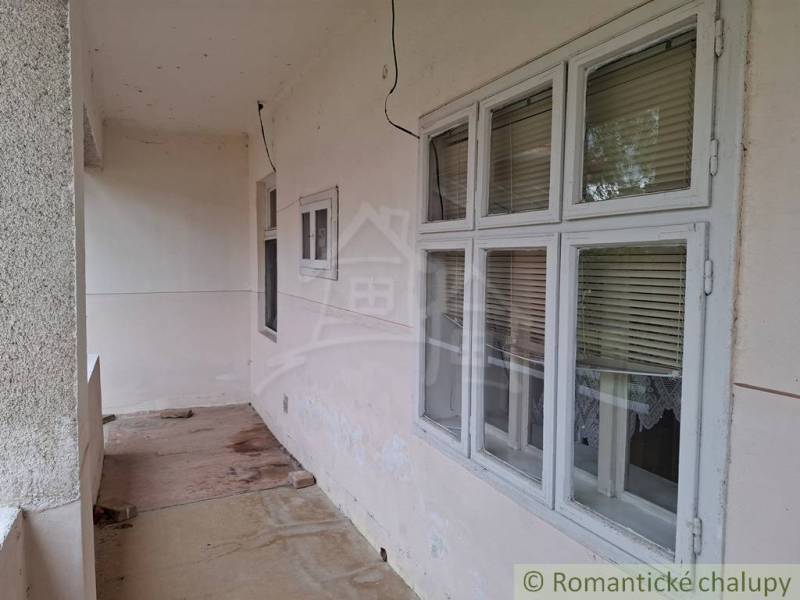 A family house in Mužla with a walkthrough terrace, windows with blinds, and a concrete floor.