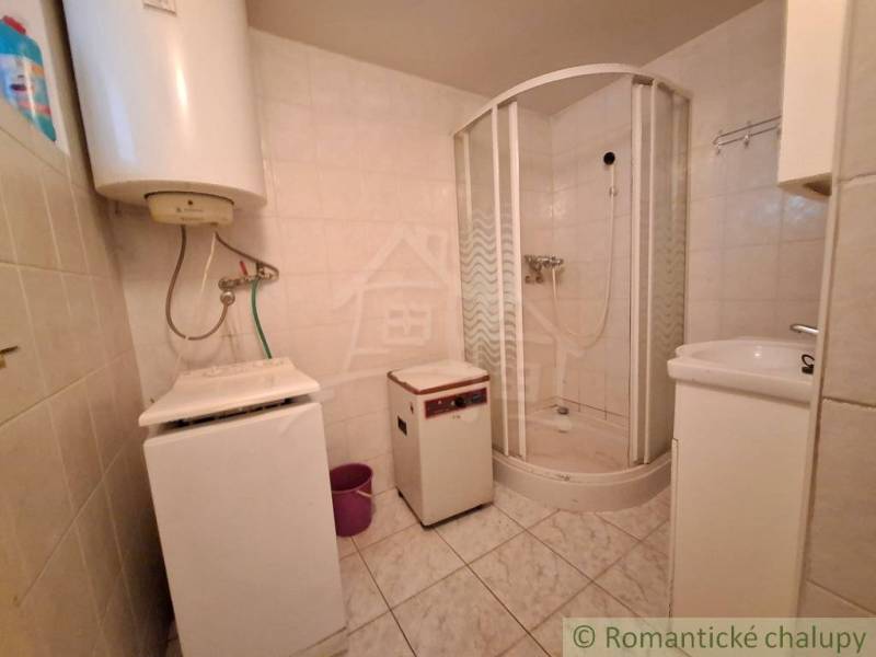 A bathroom in a family house with a shower and appliances, tiled.