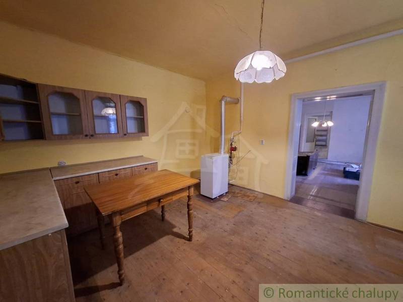 A kitchen in a family house with furniture and a light fixture, flooring with a wooden decor.