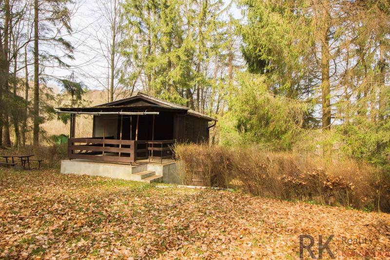 A cottage surrounded by forest on recreational land in Holčíkovce during autumn.