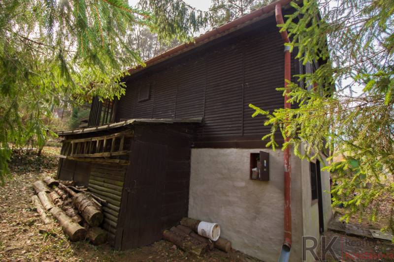 A wooden cottage surrounded by greenery on recreational land in Holčíkovce.