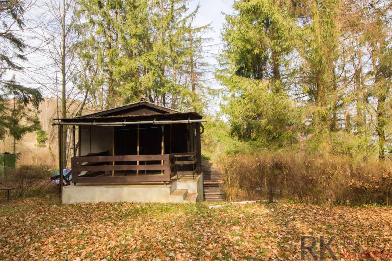 A wooden cabin surrounded by trees on recreational land in Holčíkovce.