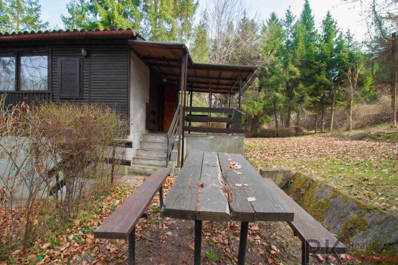 A cottage with a terrace and a table on Recreational Land in Holčíkovce, surrounded by forest.