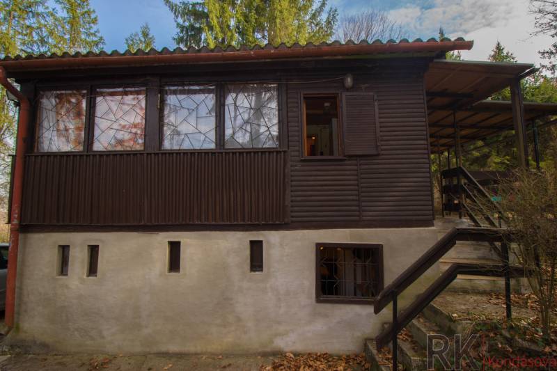 A wooden cottage on recreational land in Holčíkovce surrounded by greenery and trees.