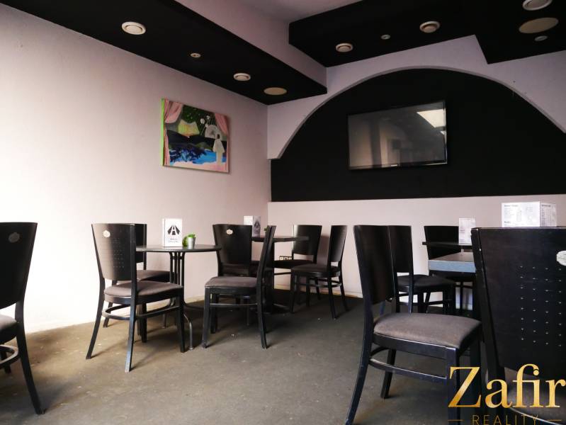 Gastro premises with black chairs, art on the wall, and a television.