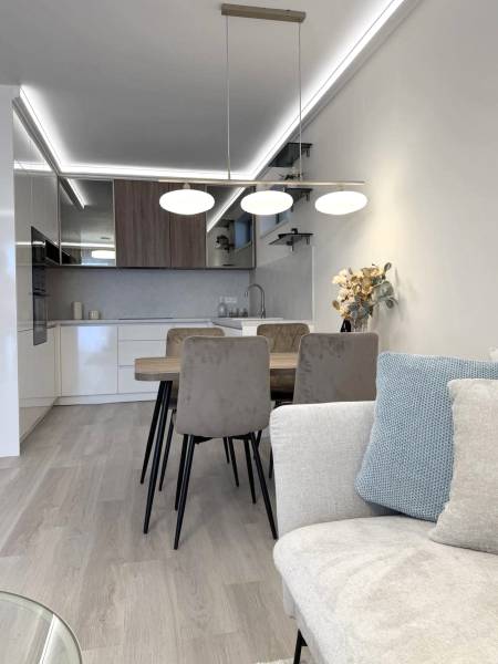 A bright kitchen with a dining table in a two-room apartment with a wooden decor floor.