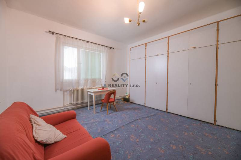 The family house includes a living room with carpeted flooring, an orange couch, and a white table.