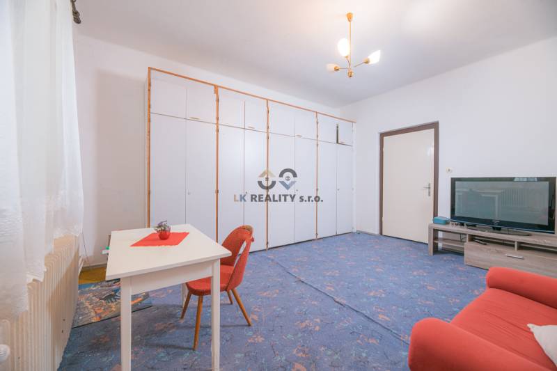 A living room in a family house with a blue carpet, a sofa bed, and storage cabinets.