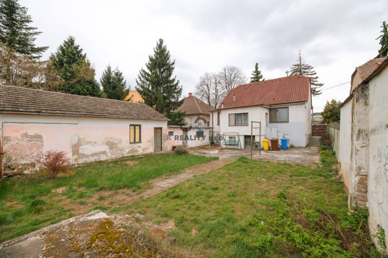 The garden and buildings of the family house on Zelenečská Street in Trnava surrounded by trees.