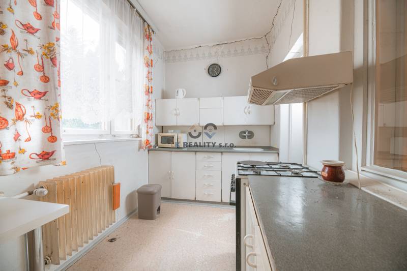 A kitchen in a family house with white cabinets, a stove, and colorful curtains.