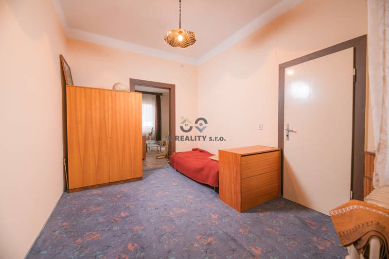A room in a family house with a blue carpet, wooden furniture, and a bed.
