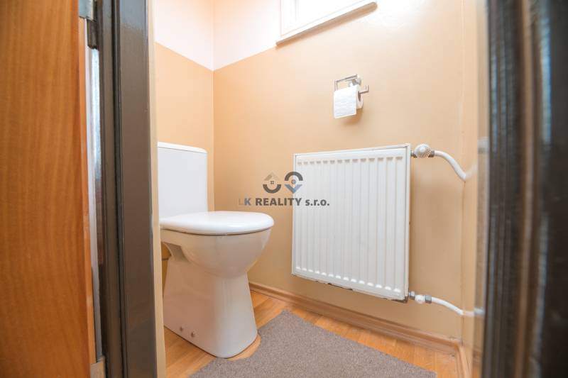 A toilet in a family house with a radiator and a floor with a wooden decor.