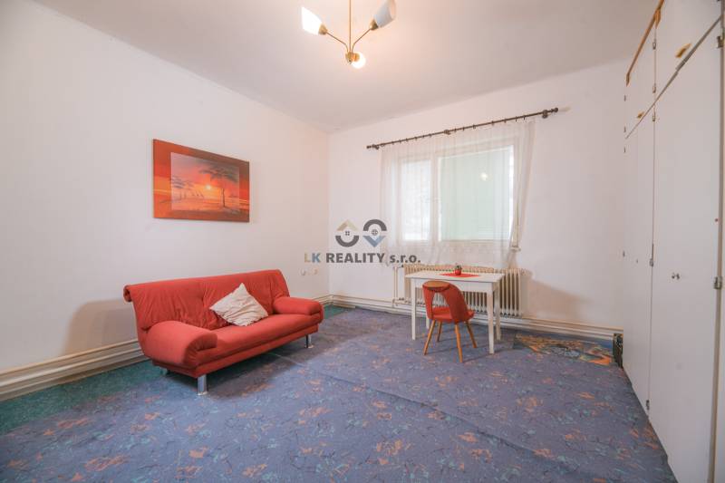 Living room in a family house with a red sofa and a table with a chair.