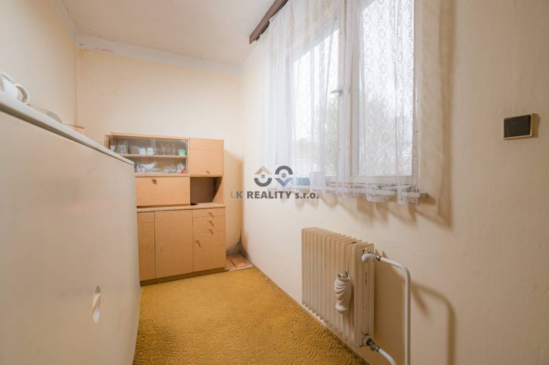 A room in a family house with older furniture, a radiator, and a carpet.