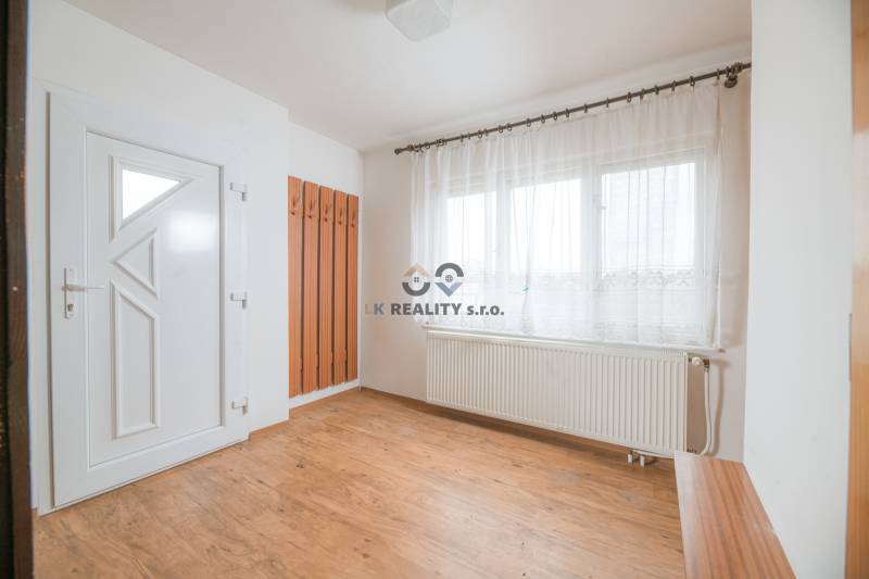 The interior of a family house with white walls, windows, and a floor with a wooden decor.