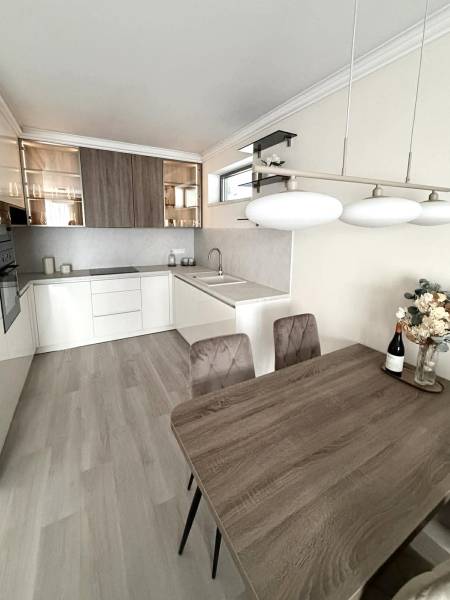 A kitchen in a 2-room apartment with a wooden decor floor, bright interior, and a dining table.