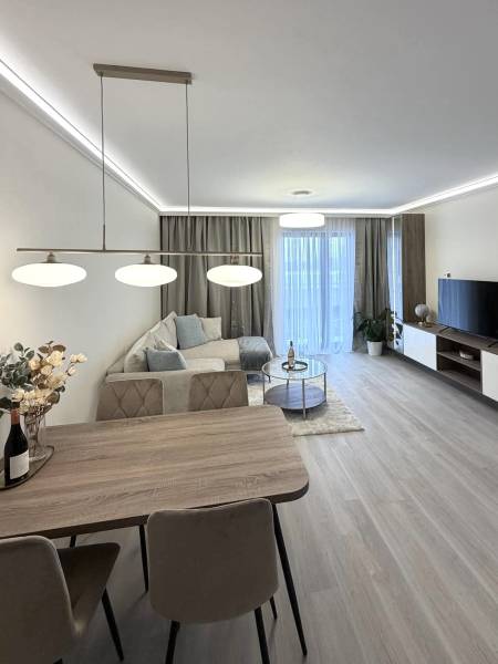 Living room with a dining table, sofa, and wooden decor flooring in a two-room apartment.