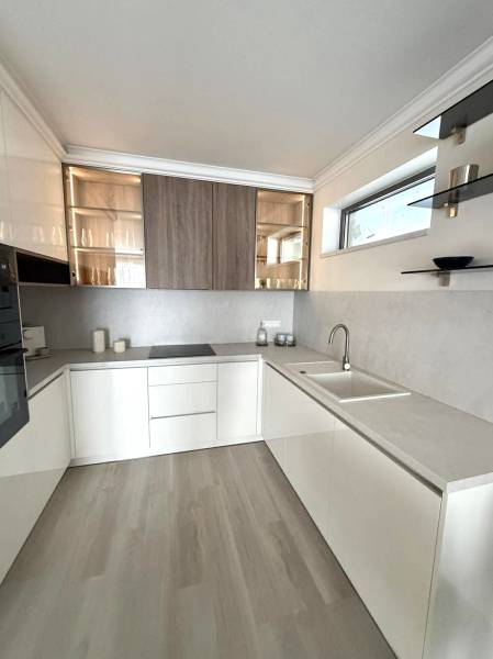 A kitchen in a 2-room apartment with white cabinets and a wood-patterned floor.