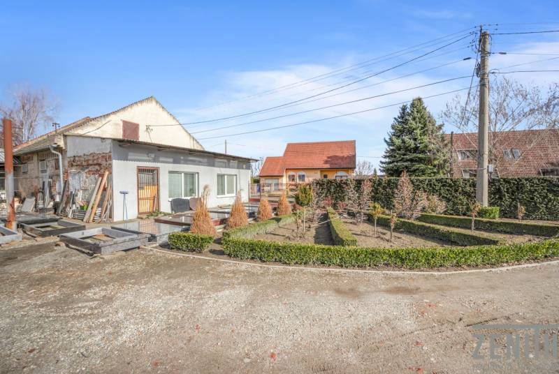 Commercial premises in Okoč with garden landscaping, surrounded by trees and shrubs.