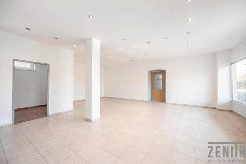 Spacious commercial spaces with white walls, tiles, and illuminated ceiling lights.