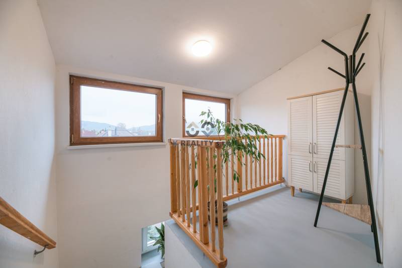 Windows with wooden frames, railing, plant, white furniture in a 2-room apartment.