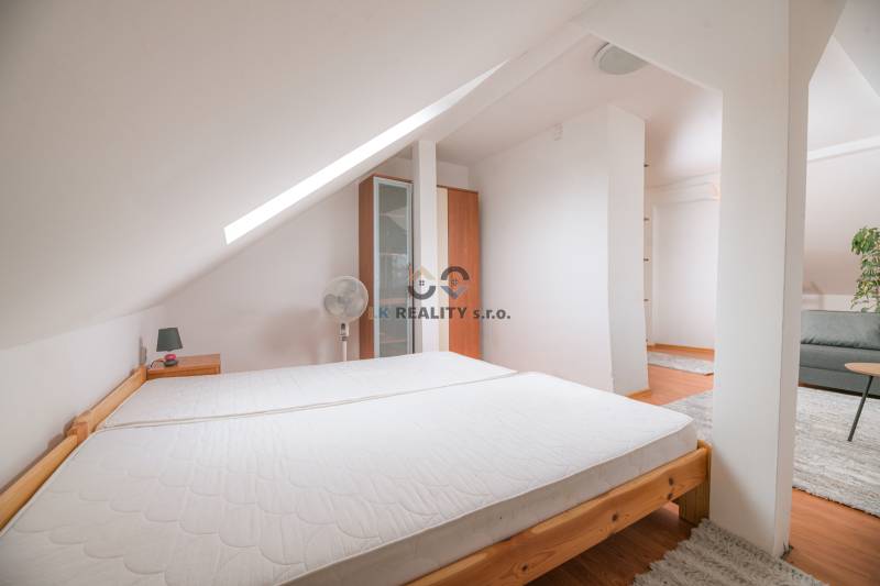 Attic bedroom in a 2-room apartment with a bed and a wardrobe, carpet on the floor.