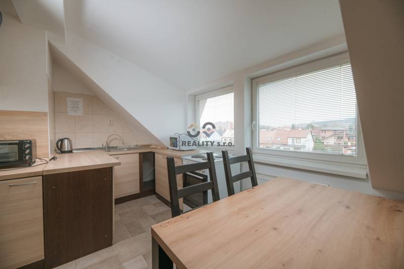 A kitchen in a 2-room apartment with a wooden decor floor, large windows with a view.