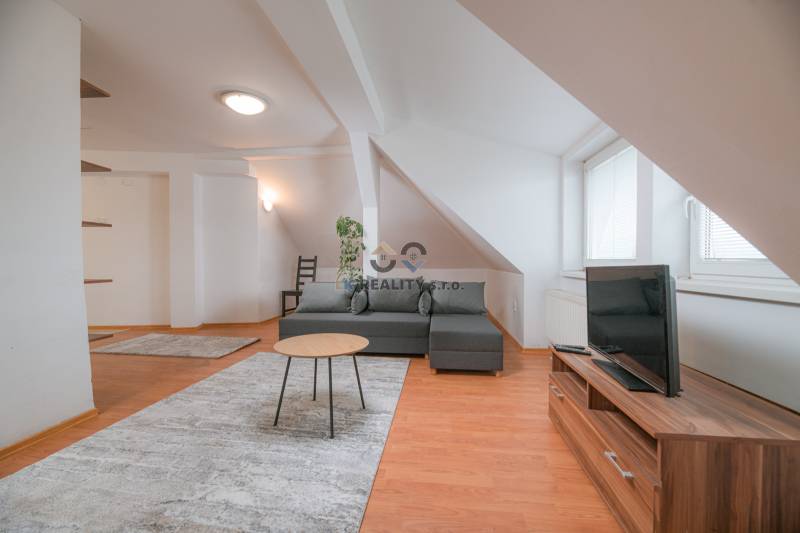 Living room in a two-room apartment with a gray sofa and a wooden patterned floor.