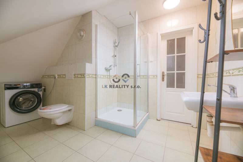 Bathroom in a 2-room apartment with a washing machine, toilet, and shower.