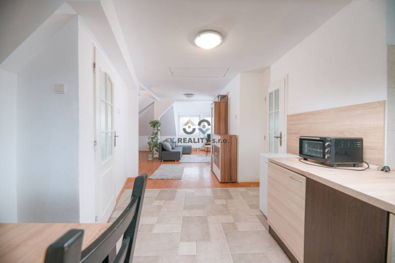 A bright kitchen connected to the living room with a wooden decor floor in a 2-room apartment.