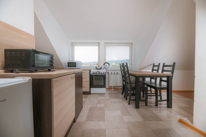 A kitchen in a 2-room apartment with a dining table, appliances, and tiles.
