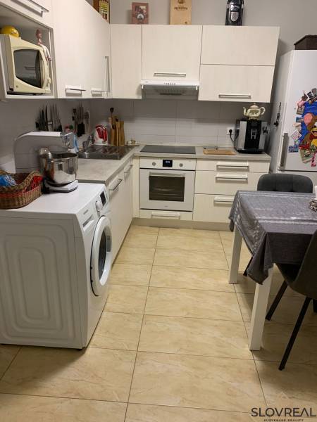 A kitchen in a 2-room apartment with white cabinets and ceramic flooring.