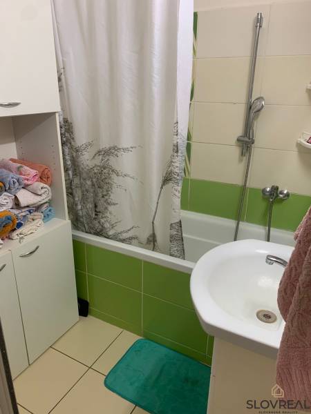 A bathroom with a bathtub and colorful tiles in a 2-room apartment.