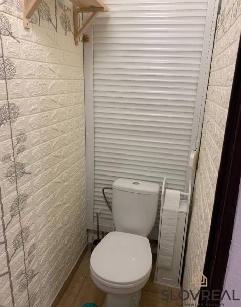 A toilet with sliding doors and a decorative wall in a 2-room apartment.