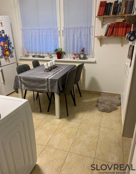 Dining area in a 2-room apartment with a white table and gray chairs.