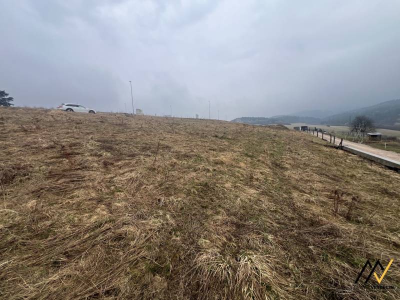 A grassy, residential plot in Stará Ľubovňa with a visible car and road.