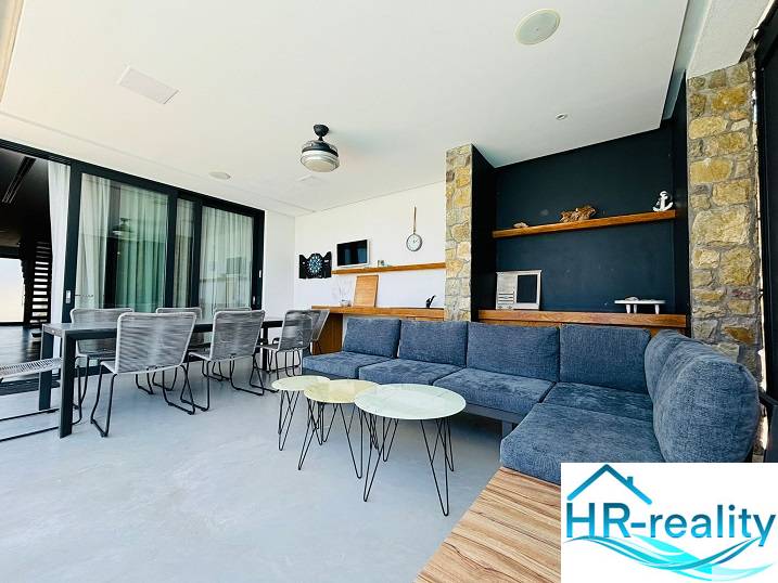 Spacious interior of a villa with stone elements and comfortable seating.