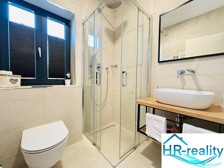 Bathroom in the villa with a shower and a sink on a wooden decor.