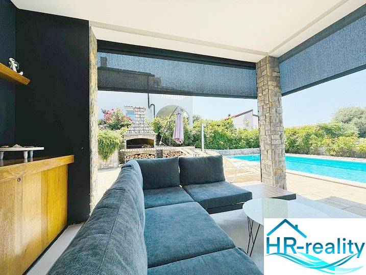 The exterior of the villa in Jakišnica with a swimming pool, seating area, and garden fireplace.