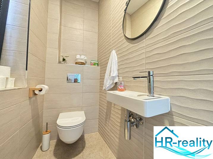Bathroom in a villa with tiled walls, a mirror, and a simple sink.