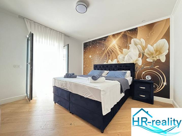 A bedroom in a villa with a decorative wall and a wooden decor floor.