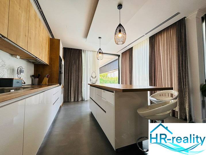 The kitchen area of the villa with stylish lighting and a wooden decor floor.